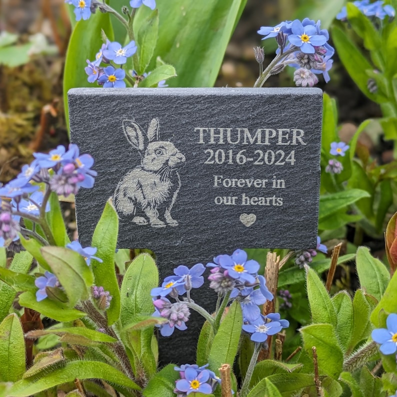Puede incluir: Un marcador de jard&iacute;n de pizarra negra con una ilustraci&oacute;n de conejo blanco y el texto "THUMPER 2016-2024 Forever in our hearts".