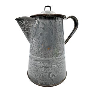 May include: A tall, gray enamel coffee pot with a speckled finish, a wide spout, a curved handle, and a removable lid with a small metal loop handle. The surface shows signs of wear with visible rust spots along the rim and body edges.
