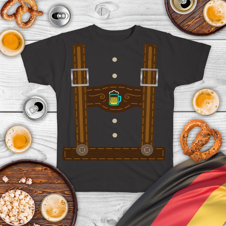 May include: A dark gray t-shirt with a brown leather lederhosen design. The design features suspenders, a beer stein, and stitching details.