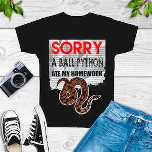 May include: Black t-shirt with a white and black graphic of a snake with the text "SORRY A BALL PYTHON ATE MY HOMEWORK" on a lined paper background.