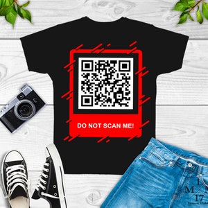 May include: Black t-shirt with a red square featuring a black and white QR code and the text "DO NOT SCAN ME!" in white. The square is surrounded by red diagonal lines.