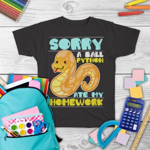 Peut inclure: Un t-shirt noir avec une image de serpent jaune en dessin animé et le texte "Désolé, un python royal a mangé mes devoirs".