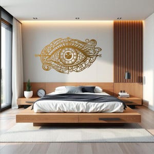 May include: A gold-colored wall decal featuring an intricate eye design with a central clock face, Roman numerals, and compass points labeled N, S, E, and W. The decorative graphic displays elaborate swirling patterns and fine line details.
