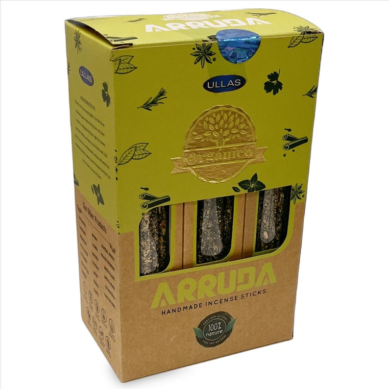 May include: A box of "ARRUDA" handmade incense sticks. The box is primarily yellow and brown, with the brand name and product description in green and white. The box features a gold foil seal that reads "Organico". The incense sticks are visible through a cutout.