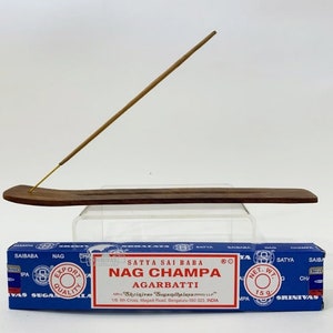 May include: A blue box of Satya Sai Baba Nag Champa incense sticks with a wooden incense holder and a single incense stick. The box reads "Satya Sai Baba Nag Champa Agarbatti" and includes the company name and address.