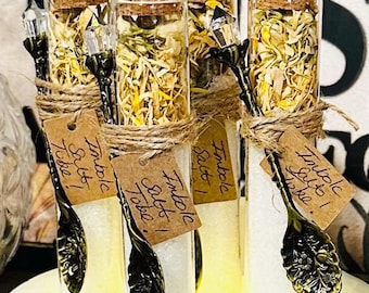 May include: Glass vials filled with white salt and yellow herbs, sealed with corks and tied with twine. Each vial has a decorative spoon and a small tag that reads "Tumble Salt! Take!"