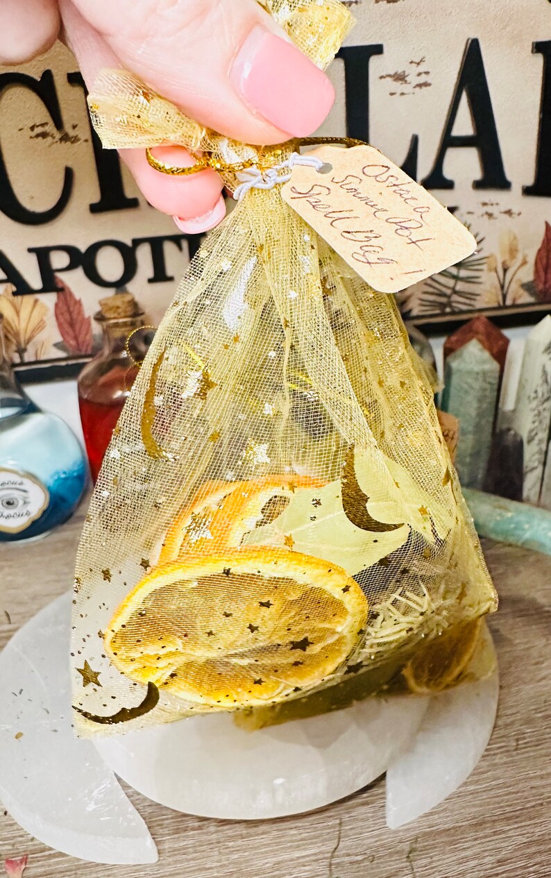 May include: A small, gold mesh bag filled with dried orange slices, herbs, and a handwritten tag that reads "Ostie Bot!  Smell My Bag!"