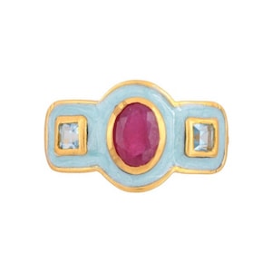 May include: A gold ring with a light blue enamel setting. The ring features a red oval gemstone surrounded by two smaller square gemstones.