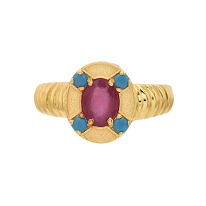 Puede incluir: Un anillo de oro con una piedra ovalada roja rodeada de piedras azules más pequeñas.