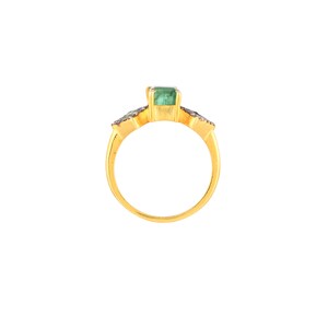 Front view of ring on white background, showing bezel-set emerald and oxidized diamond halos