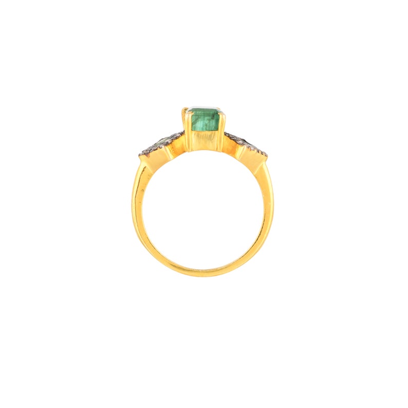 Front view of ring on white background, showing bezel-set emerald and oxidized diamond halos