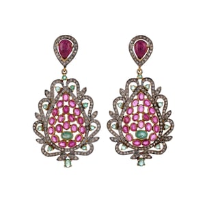 May include: A pair of dangle earrings with a teardrop design. The earrings are made of silver and feature a cluster of pink and green gemstones.