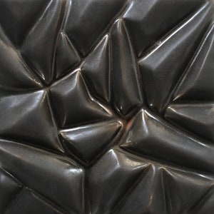 May include: A black ceramic tile with a textured, geometric pattern. The tile has a glossy finish and a three-dimensional design.