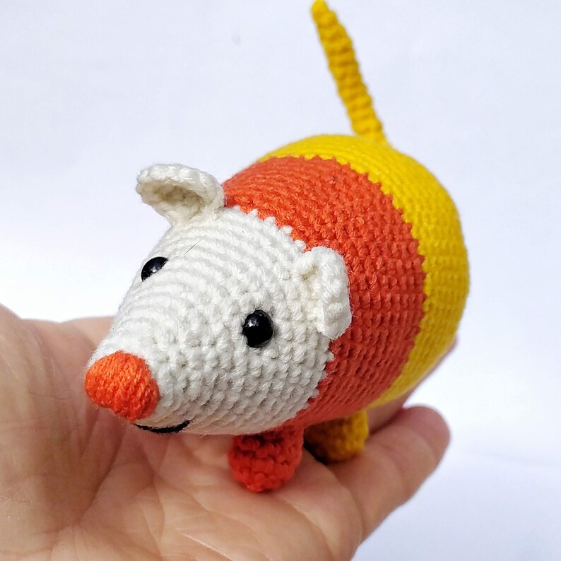 Pu&ograve; includere: Un piccolo topo giocattolo realizzato all'uncinetto a mano con un design a blocchi di colore che ricorda le caramelle candy corn. La testa &egrave; color crema con un naso arancione brillante e occhi a perla neri, con corpo a sezioni arancioni e gialle.