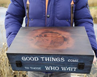 May include: A wooden box with a dark brown stain and a burnt design on the lid. The lid has the text "Good Things Come To Those Who Wait" in white lettering. The box has two black metal latches.