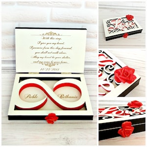 May include: A white wooden ring box with a red infinity symbol design. The box is open and the infinity symbol has two compartments with the names "Pablo" and "Bethanie" inscribed. The lid of the box has a poem about love and a date, "11/23/2018".