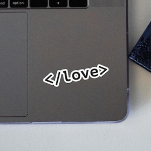 May include: A laptop computer with a sticker that says "</love>" on the lid.