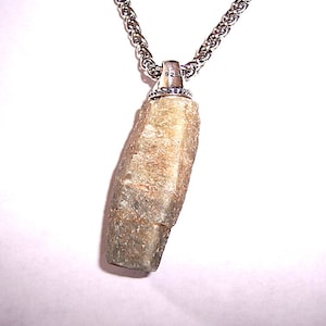 May include: A silver chain necklace with a pendant made of a rough, gray, and brown stone. The pendant is attached to the chain with a silver bail that has the number "925" stamped on it.