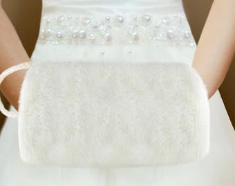 May include: White faux fur bridal wristlet with a rope handle.