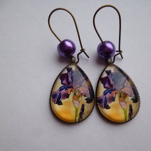 Peut inclure: Boucles d'oreilles en forme de goutte d'eau avec une fleur violette et jaune et des perles violettes.