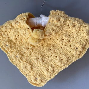 Poncho bébé au crochet jaune.
