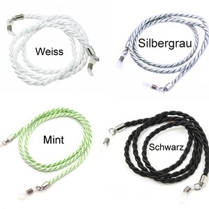 May include: Four different colors of braided eyeglass cords. The cords are white, silver gray, mint green, and black. Each cord has two metal clasps on the ends.