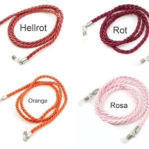 May include: Four different colors of braided cord eyeglass holders. The colors are orange, pink, red, and dark red. The cords are made of a soft, braided material and have metal clasps on each end.
