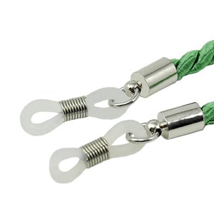 May include: Green braided cord eyeglasses retainer with silver metal ends and clear plastic loops.