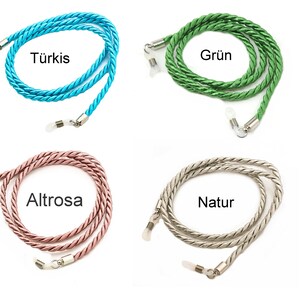 May include: Four different colored eyeglass chains. The chains are made of twisted rope and have silver metal clasps. The colors are turquoise, green, pink, and silver. The text on the image reads "T&uuml;rkis", "Gr&uuml;n", "Altrose", and "Natur".