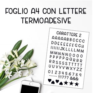 Peut inclure: Une feuille de papier blanche avec du texte noir qui dit "FOGLIO A4 CON LETTERE TERMOADESIVE CARATTERE 2" et liste l'alphabet, les chiffres de 0 à 9, les signes de ponctuation et les symboles. Le papier est sur une surface blanche avec un smartphone blanc, une bouteille en verre transparente et une bouteille noire.