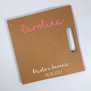 Peut inclure: Un sac cadeau carr&eacute; marron avec une d&eacute;coupe pour la poign&eacute;e. Le nom "carolina" est &eacute;crit en rose en haut, et en dessous, en blanc, les noms "Paolo e Serena" et la date "05.06.2022".