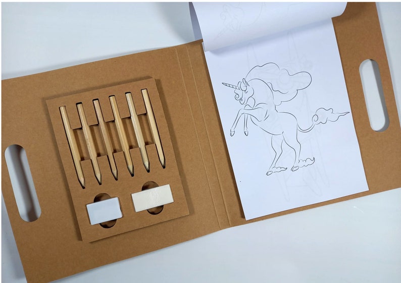 Peut inclure: Un kit de bricolage dans un &eacute;tui en carton brun, contenant six crayons en bois et deux gommes. Un livre de coloriage avec un contour de licorne est ouvert. Le kit est pour les activit&eacute;s cr&eacute;atives.