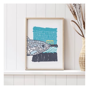 May include: A framed print with a blue and white abstract design featuring a stylised fish and geometric shapes. The print has a white background and a light wood frame.
