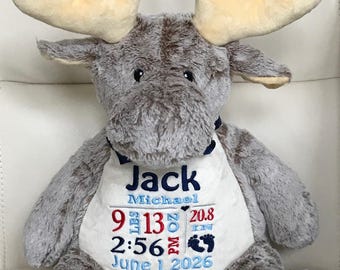 May include: A plush grey moose stuffed animal wearing a white bib embroidered with the name Jack Michael, birth details including 9 lbs 13 oz, 20.8 in, 2:56 PM, and the date June 1, 2026, featuring dark blue, light blue, and red thread.
