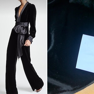 May include: A black velvet jumpsuit with a wide, satin sash tied in a bow at the waist. The jumpsuit has a deep V-neckline and long sleeves.