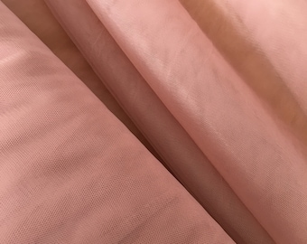 May include: Close-up of a soft, pink tulle fabric with a fine mesh texture. The fabric is folded and draped, creating a delicate and airy look.