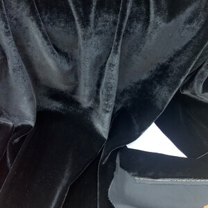 May include: Black velvet fabric with a smooth, soft texture. The fabric is folded and draped, showing the rich, deep color.