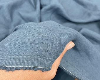 May include: A close-up of a piece of blue linen fabric with a raw edge. The fabric is soft and textured, and it has a slightly faded look.