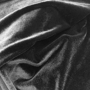May include: Black velvet fabric with a soft, smooth texture and a subtle sheen. The fabric is draped and folded, creating a luxurious and elegant look.