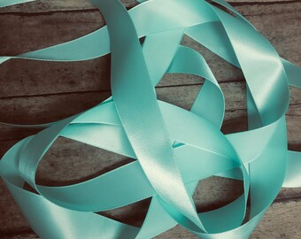 May include: A pile of light blue satin ribbon on a wooden surface.