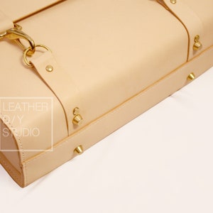 May include: A light beige leather satchel with brass hardware and the text "LEATHER DIY STUDIO" on the side.