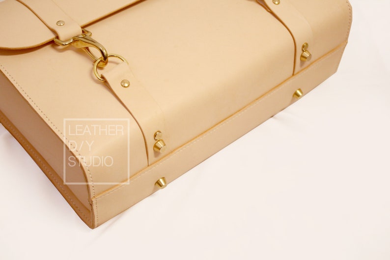 May include: A light beige leather satchel with brass hardware and the text "LEATHER DIY STUDIO" on the side.