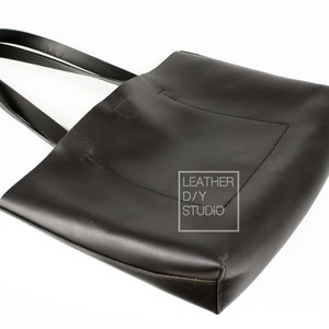May include: A black leather tote bag with double straps. The bag has a small pocket on the front and the text "LEATHER D/Y STUDIO" is printed on a white rectangle.