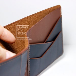 May include: A brown leather wallet with a blue leather interior. The wallet has multiple card slots and a billfold. The wallet is open and the interior is visible. The text "LEATHER D/Y STUDIO" and "LEATHERDIYSTUDIO.COM" is printed on the interior of the wallet.