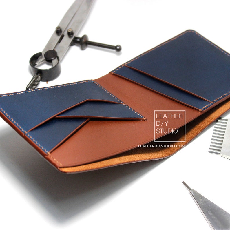 May include: A brown leather wallet with a blue leather interior. The wallet is open and the interior is visible. The wallet has multiple card slots and a billfold. The wallet is made of high-quality leather and has a stitched edge.
