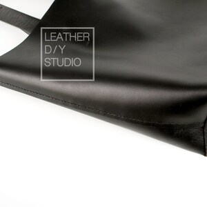 May include: Black leather tote bag with a stitched seam and a small white label that reads "LEATHER D/Y STUDIO".