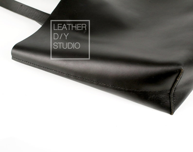 May include: Black leather tote bag with a stitched seam and a small white label that reads "LEATHER D/Y STUDIO".