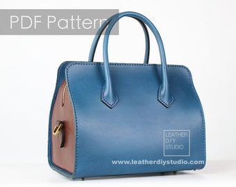 May include: A blue leather handbag with brown leather accents and a brass clasp. The bag has a top handle and a zipper closure. The bag is labeled "Leather DIY Studio" and "www.leatherdiystudio.com".