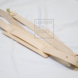 May include: A light brown leather camera strap with a gold metal buckle and two adjustable straps. The strap has the text "LEATHER D/Y STUDIO" printed on it.