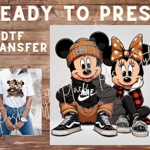 May include: A digital transfer design featuring Mickey Mouse and Minnie Mouse wearing casual streetwear. Mickey is wearing a brown beanie, a black hoodie with a white Nike swoosh, brown pants, and black and white sneakers. Minnie is wearing a red and black plaid shirt, a black jacket, and black and white sneakers. The design is ready to be pressed onto a t-shirt or other apparel.